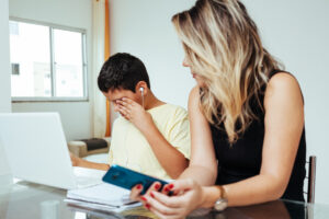 Mother helping sad son to do homework.